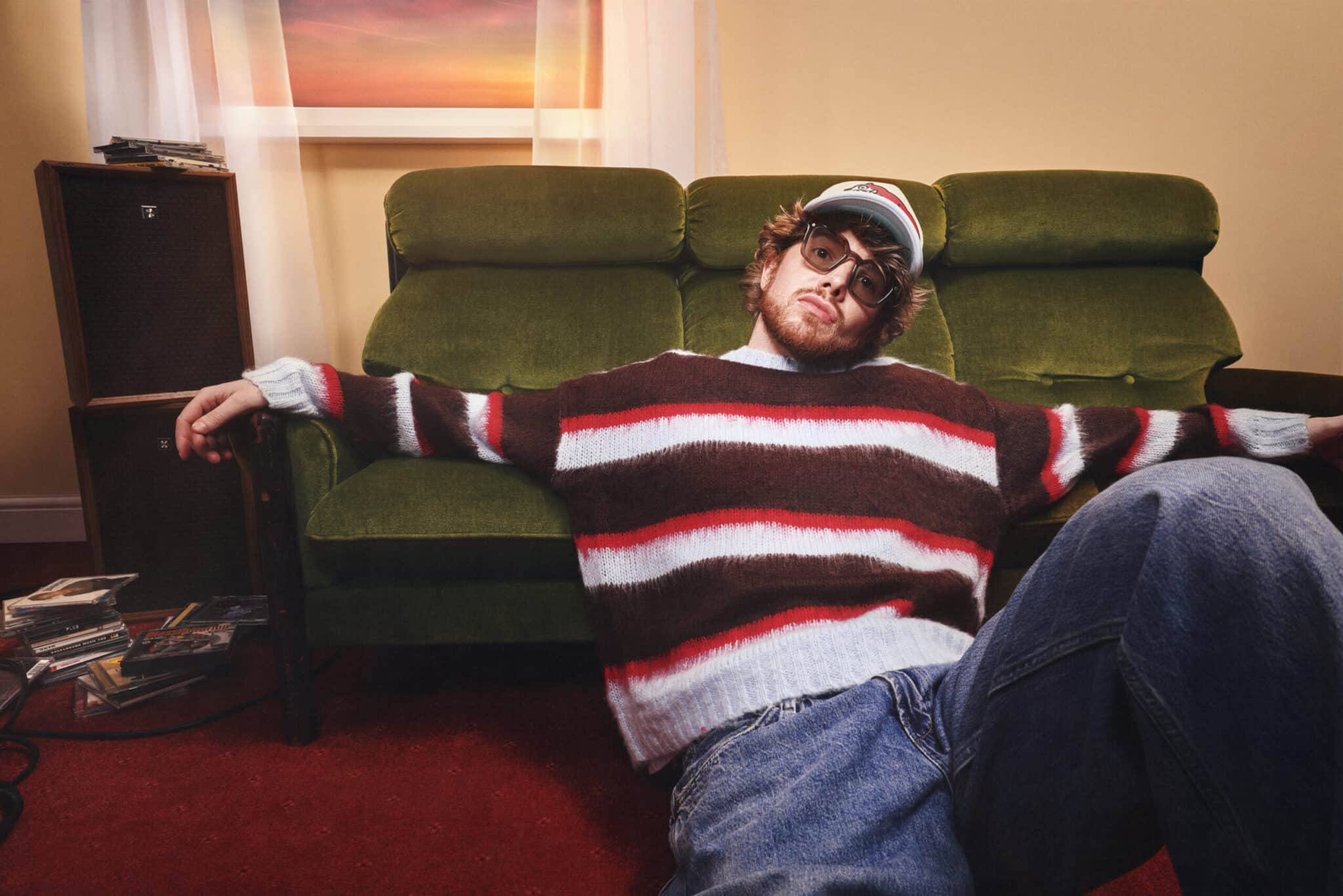 ADMT sits at the base of a sofa looking directly at the camera