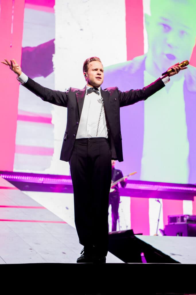 Olly Murs performing at First Direct Arena, Leeds, surrounded by bright lights and cheering fans
