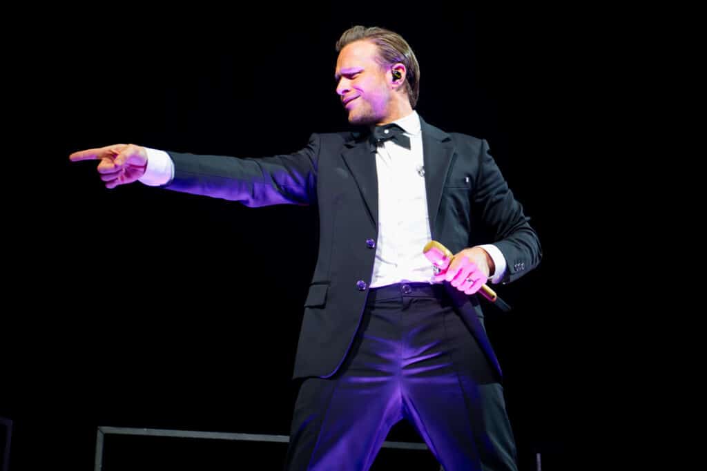 Olly Murs performing at First Direct Arena, Leeds, surrounded by bright lights and cheering fans