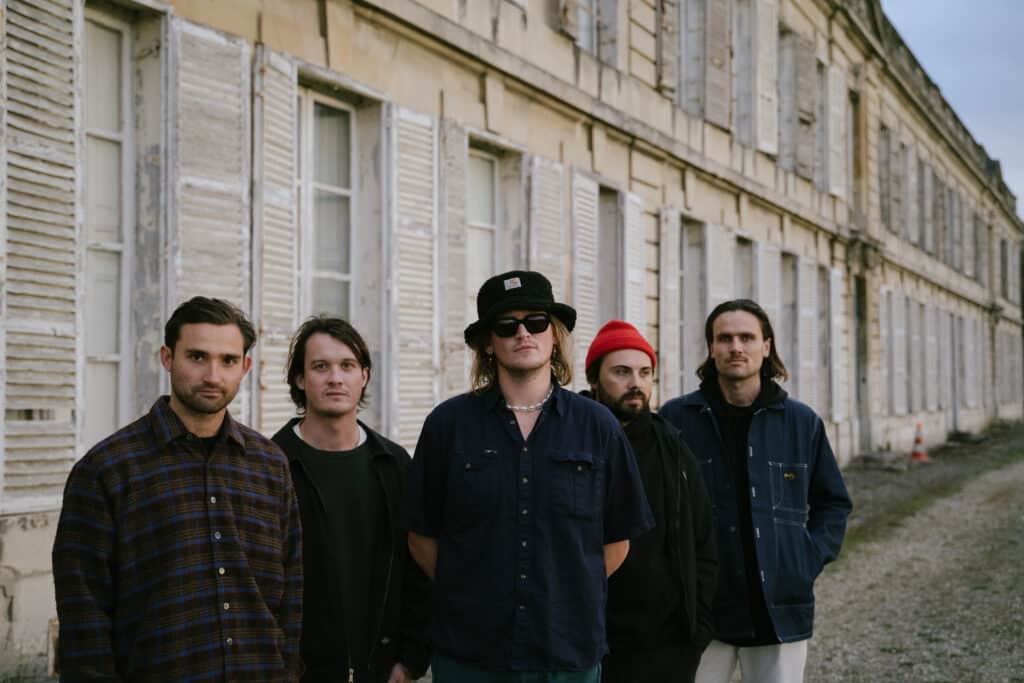 The 5 members of the band NO CIGAR stand outside a building wearing dark clothing