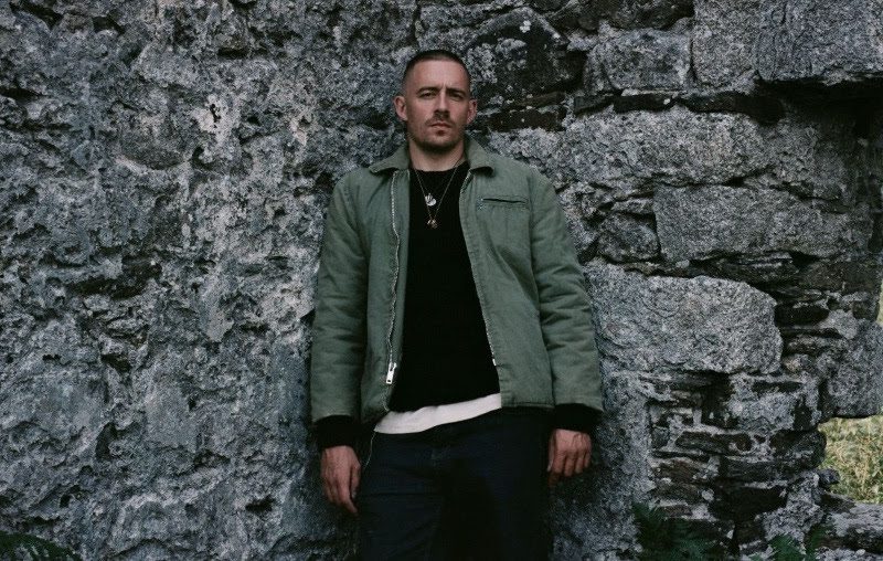 Dermot Kennedy stands against a stone wall