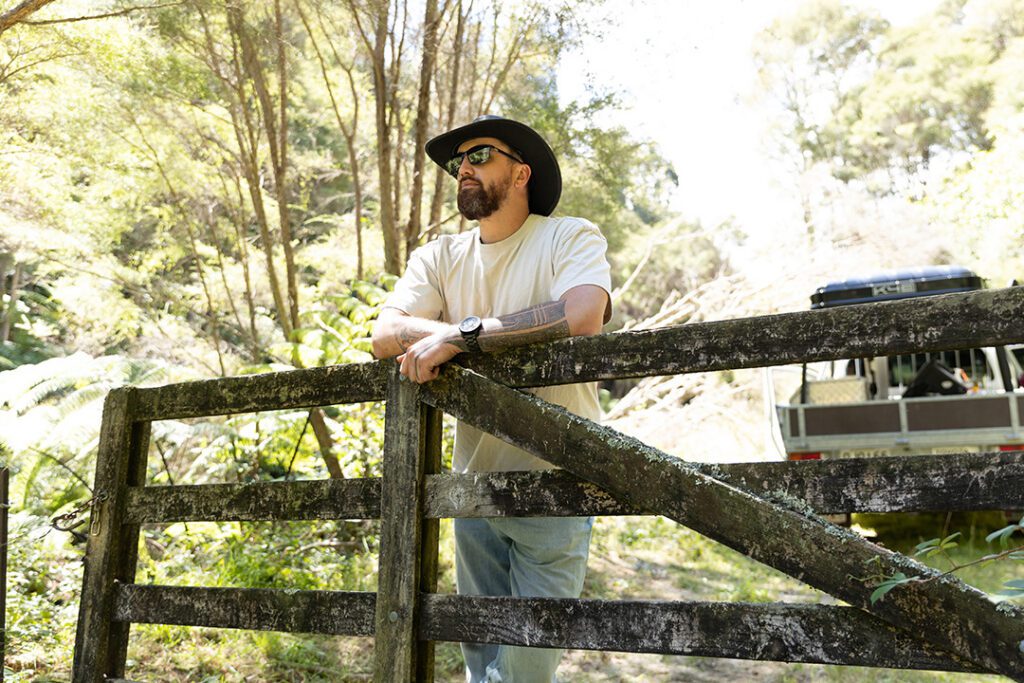 Te Wehi stood in a cowboy hat leaning on a wooden gate
