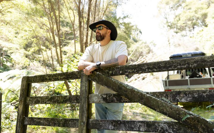Te Wehi stood in a cowboy hat leaning on a wooden gate