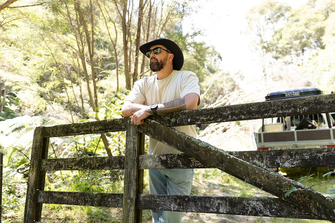 Te Wehi stood in a cowboy hat leaning on a wooden gate